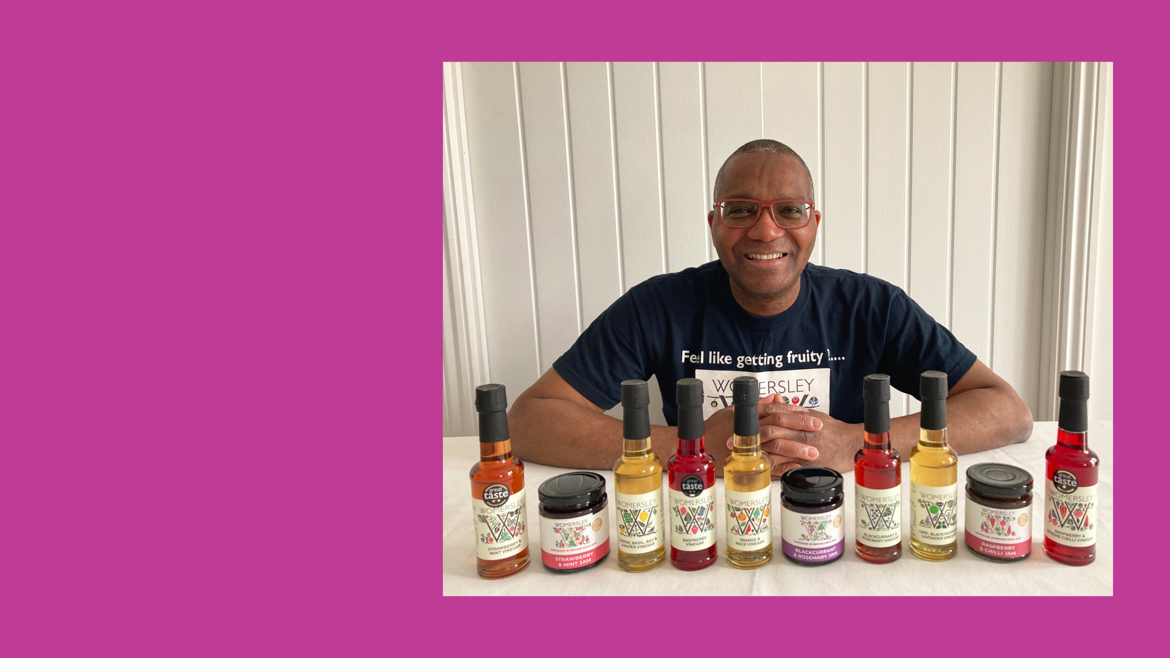 Picture of Labaika smiling and sitting behind a row of Womersley Foods bottles Fruit Vinegars.