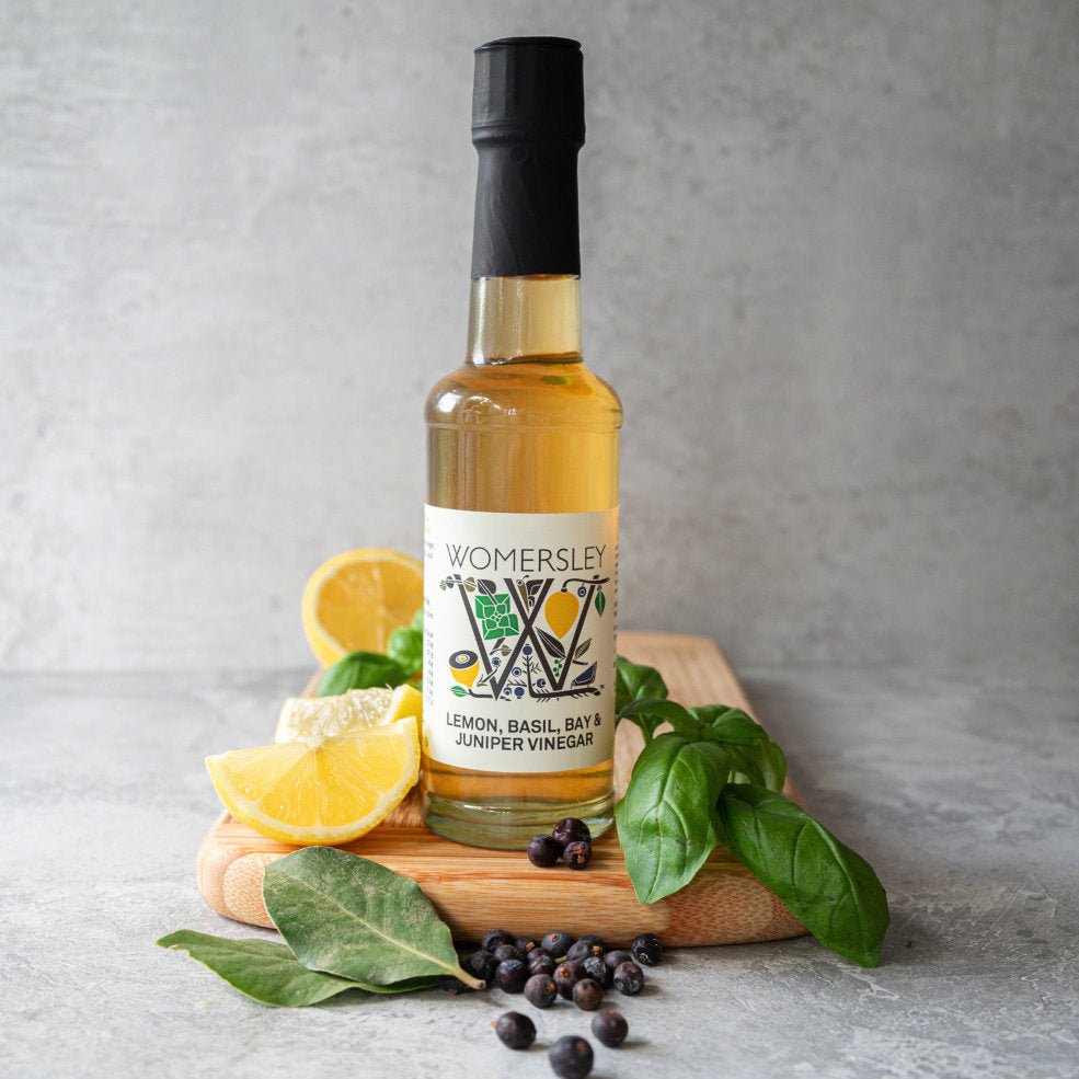 Womersley Foods Lemon Basil Bay and Juniper Vinegar 150ml bottle with fresh lemons, basil leaves and juniper berries