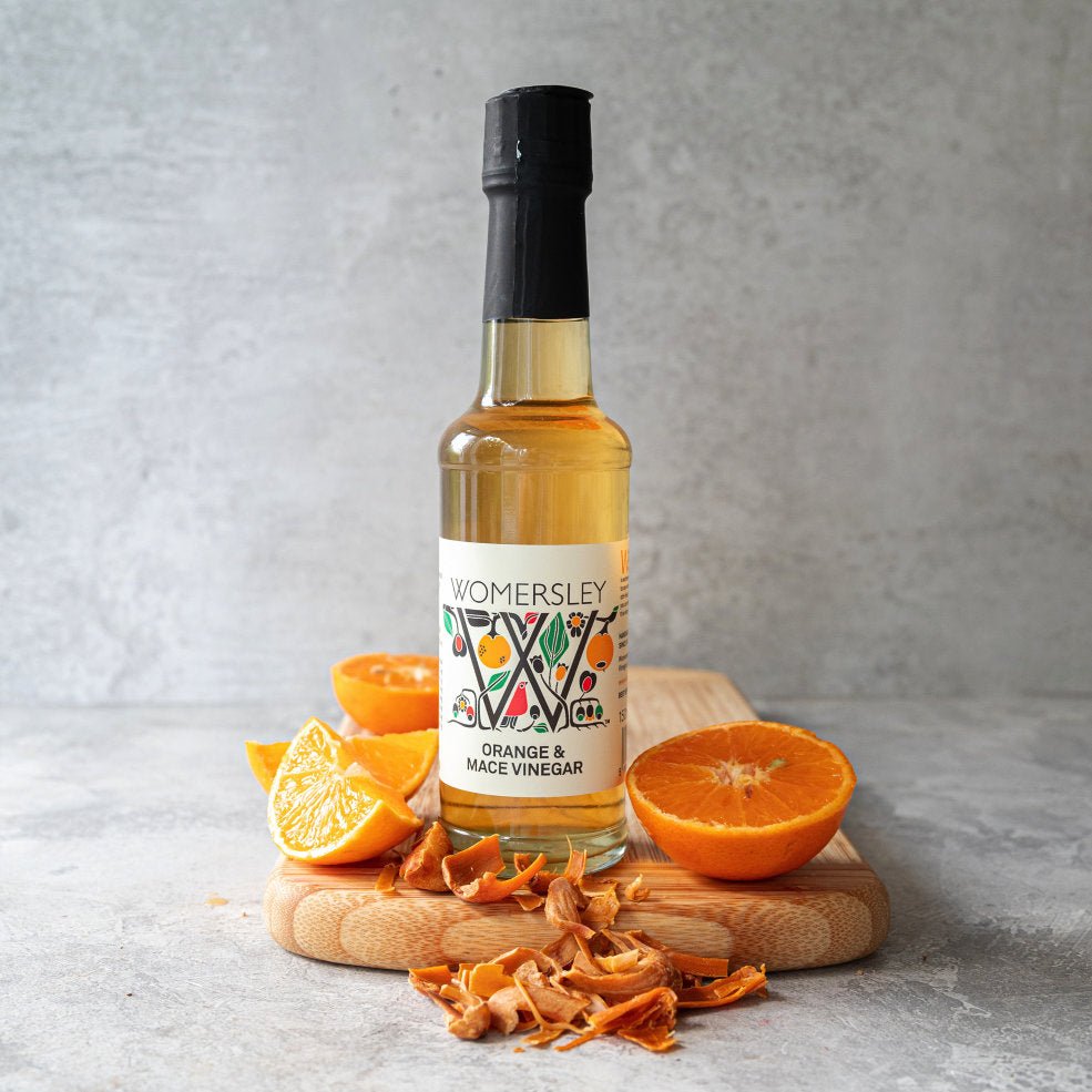 Womersley Foods Orange and Mace Vinegar 150ml bottle with fresh oranges and dried mace on wooden board