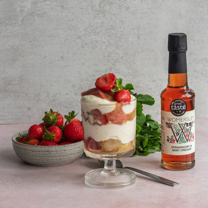 Square Womersley Foods Strawberry & Mint Vinegar bottle used to make strawberry ice cream in an ice cream cup with a bowl of strawberry and mint leaf.