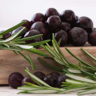 Blackcurrant fruits and Rosemary leaves on a cutting board.